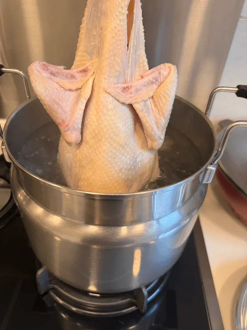 Chicken being immersed in boiling water